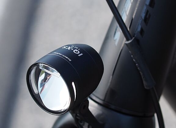 Schwarzer LED-Fahrradscheinwerfer am silbernen Fahrradlenker montiert.