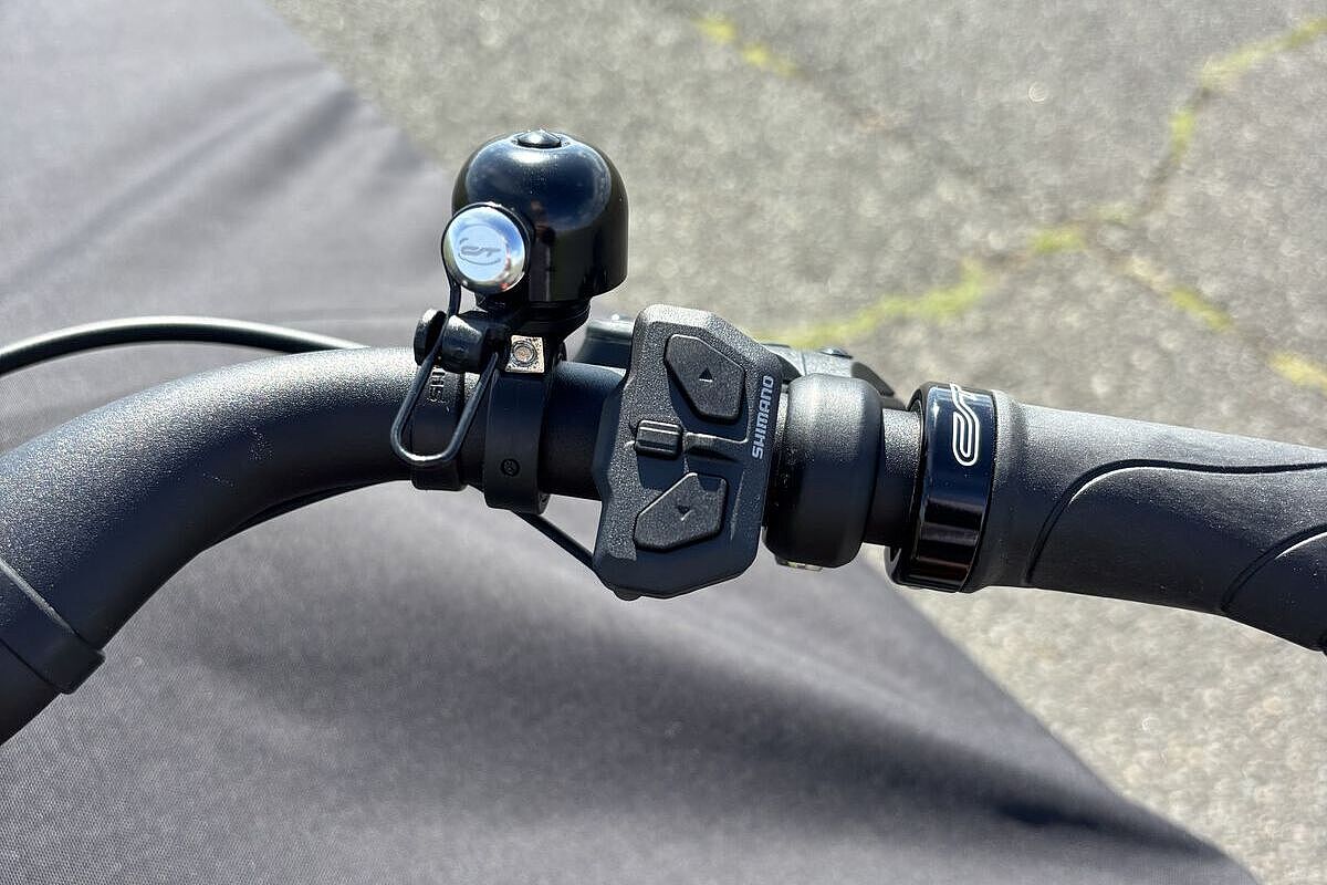 Chike Schalter Ein Fahrradlenker mit einer kleinen schwarzen Klingel und zwei Tasten zur Bedienung des E‑Bikes.